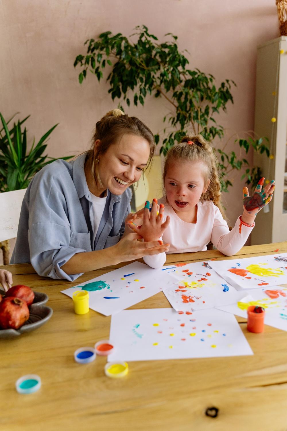 Une éducatrice et une enfant font de la peinture.